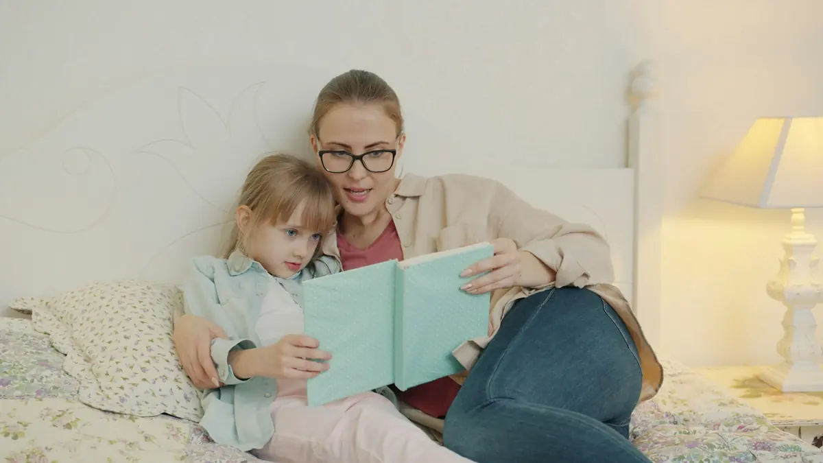 Annesiyle birlikte kitap okuyan bir kız çocuğu